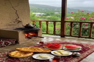 ایوان خانه ای روستایی در منطقه ای سرسبز با صبحانه محلی همراه نان تازه