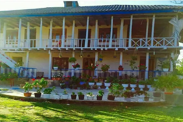 خانه ای با دوطبقه ساخته شده از چوب در شمال ایران با گلدانهای زیبا در محوطه حیاط جلوی تراس