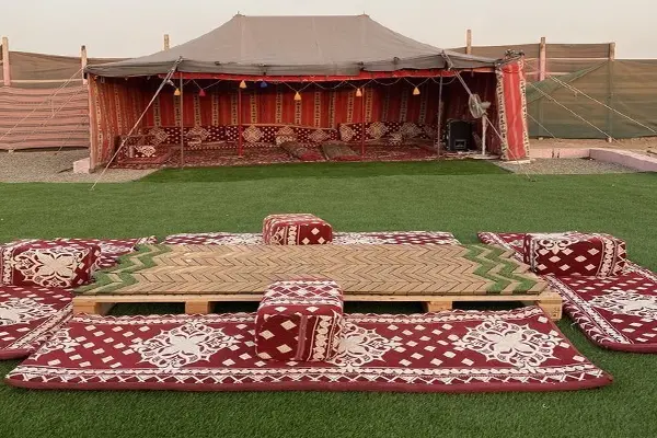 چادر سنتی اقامتگاه بومگردی با فرشها و پشتیهای محلی در فضای باز