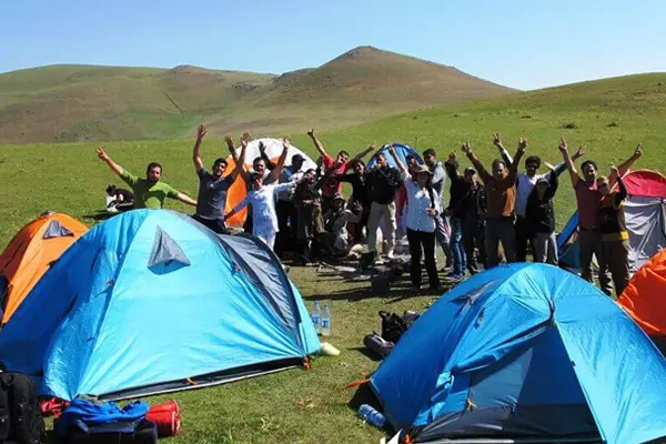 تعدادی چادر کمپینک،گروهی از زنان و مردان در طبیعت سرسبز